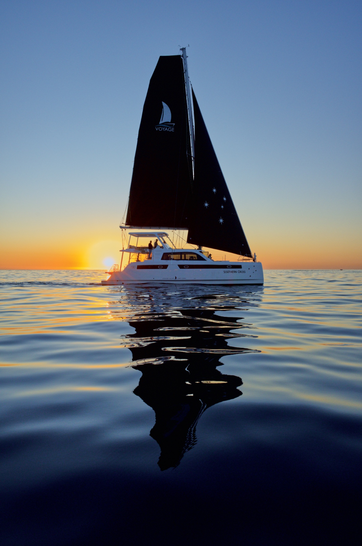 VOYAGE catamaran sailing at sunset